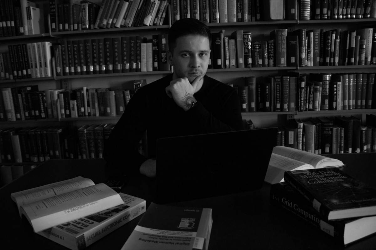Vlad at a library table with a laptop and open books